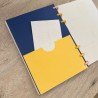 Bolsillo para notas amarillo y azul visto desde la contraportada de la agenda 2026-27, diseño Plumas